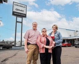 Mary Ann Wheeler standing in front of Dealership with her childern, Daniel and Mary Jo